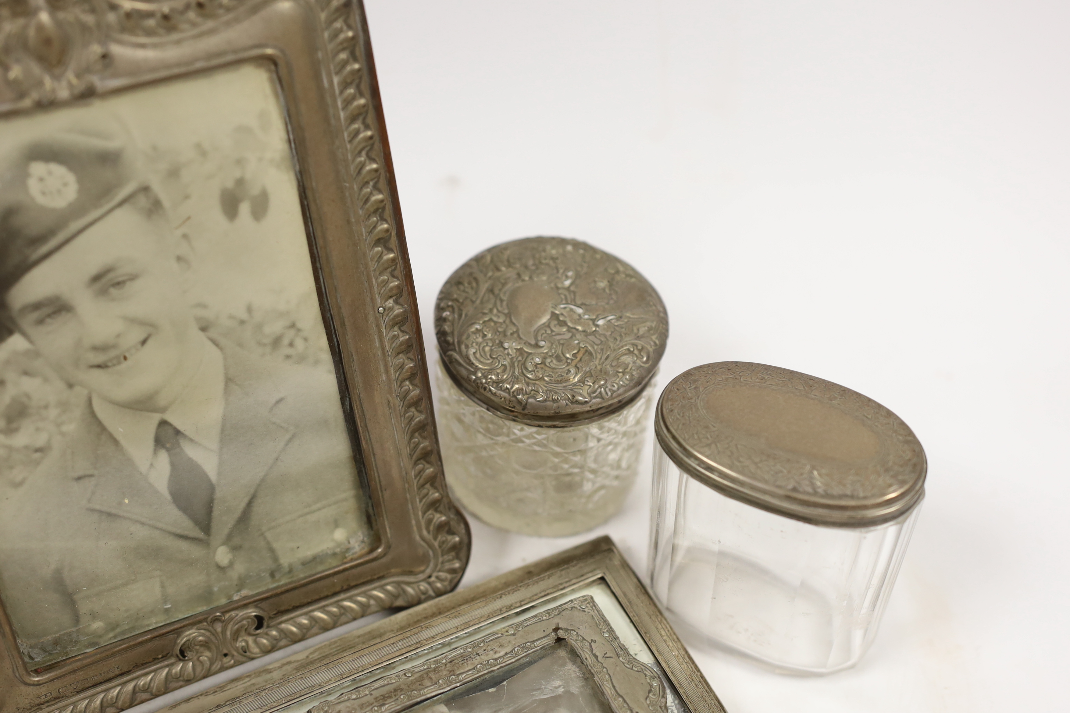 Four assorted early 20th century silver mounted photograph frames, largest 19.5cm (a.f.) five assorted silver mounted glass toilet jars and a small pair of silver handled scissors.